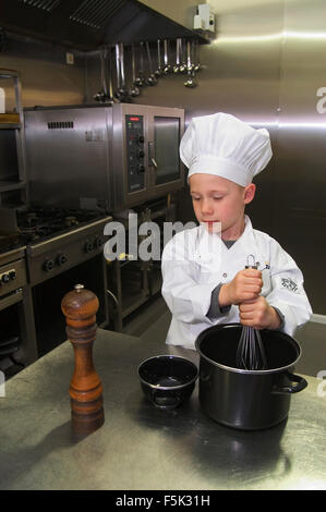 Enfant de Cook's costume avec chapeau de chef cooking in restaurant kitchen Banque D'Images