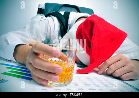 Un homme avec un chapeau de Père Noël dormir dans son bureau après un party de Noël de bureau Banque D'Images