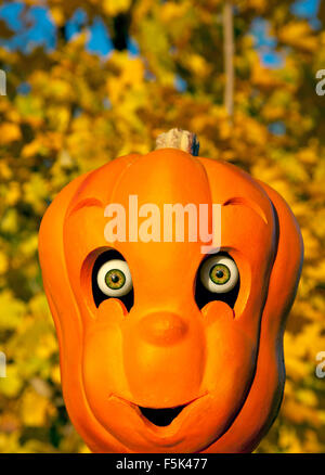 Halloween citrouille sculptée jouet avec des yeux réalistes et un arbre d'automne dans l'arrière-plan, 2015. Banque D'Images