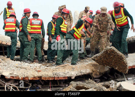 Les responsables de l'armée pakistanaise et sauve deux occupé dans l'opération de recherche de sauvetage pour les victimes dans les décombres d'une usine s'est effondrée sur le site de l'accident après l'effondrement des bâtiments de l'usine à Sundar Industrial Estate près de Lahore le Jeudi, Novembre 05, 2015. Au moins 23 morts, des dizaines toujours prisonniers après l'effondrement de l' usine à Sundar Industrial Estate, le mercredi soir. Quatre étages d'une usine de production de sacs en plastique s'est effondré, le piégeage des douzaines de travailleurs sous les décombres à l'Sundar Industrial Estate près de Lahore. Banque D'Images