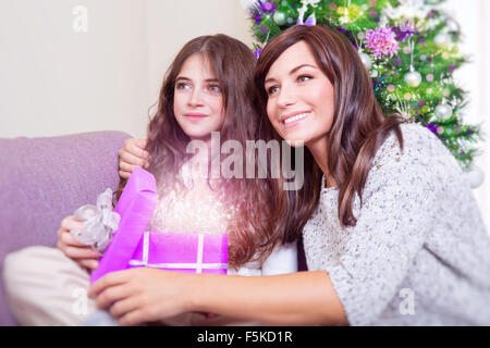 Portrait de belle mère avec mignon fille avec plaisir l'ouverture de boîte-cadeau, recevant un présent magique Banque D'Images