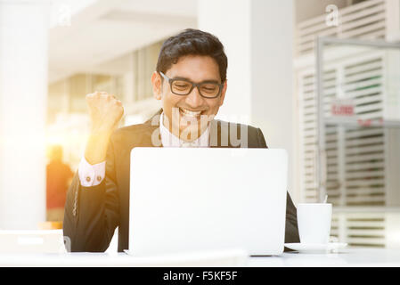 Les jeunes gens d'affaires Indiens asiatiques des succès à célébrer, à l'aide d'un ordinateur portable au café, avec une tasse de café. L'Inde, l'homme d'affaires hommes m Banque D'Images