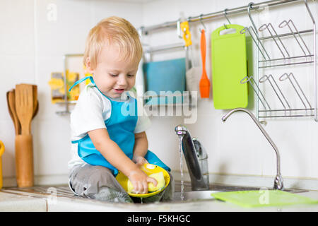 Enfant mignon garçon 2 ans lave-up dans la cuisine Banque D'Images