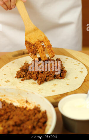 Mettre partie de la farce (viande hachée) sur les tortillas. La tortilla de boeuf. enchilada Série. Banque D'Images