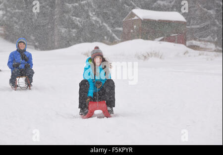 Les enfants glisser sur la neige en traîneau Banque D'Images