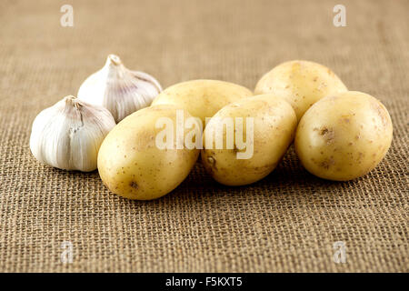 Les pommes de terre et l'ail sur fond biologique jute rustique Banque D'Images