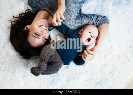 Mère couchée sur un tapis avec bébé fils, overhead view Banque D'Images