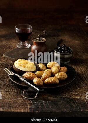 Pommes de terre rôties avec bol de la fondue parmesan sur plat rustique Banque D'Images