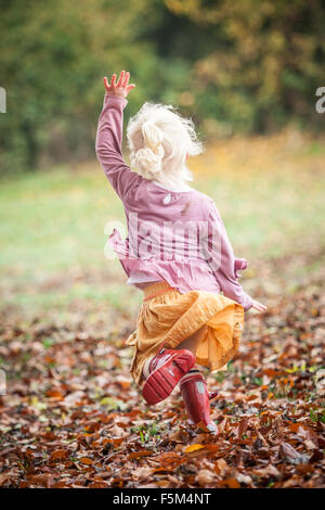 Fillette de trois ans jouant dans un cadre verdoyant du parc de l'automne. Banque D'Images