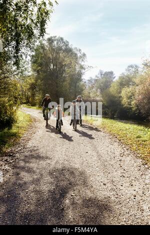 Vue avant du family riding bicycles on rural road Banque D'Images