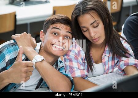 Portrait of teenage boy with cheesy grin et fille avec les yeux fermés dans la classe Banque D'Images