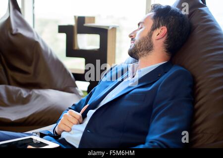 Jeune homme designer dormir sur des chaises pouf in office Banque D'Images