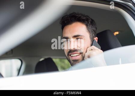 Young businessman talking on smartphone in car Banque D'Images