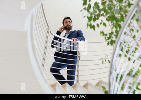 Young businessman talking on smartphone sur office stairway Banque D'Images