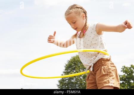 Low angle view of girl hula hoop, bras ouverts à la bas Banque D'Images