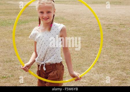 Girl looking through hula hoop smiling at camera Banque D'Images