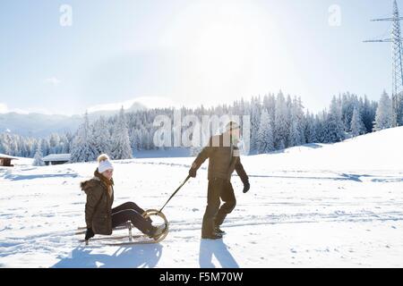 Vue latérale du man a senior woman on sled, Sattelbergalm, Tyrol, Autriche Banque D'Images