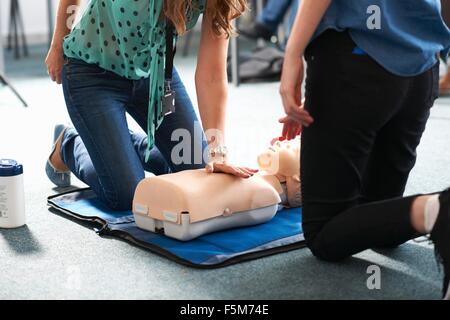 College student performing CPR on mannequin in class Banque D'Images