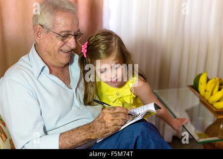 Girl looking at grand-père écrit dans l'ordinateur portable Banque D'Images