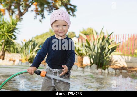 Female toddler jouer avec de l'eau arrosage de jardin Banque D'Images