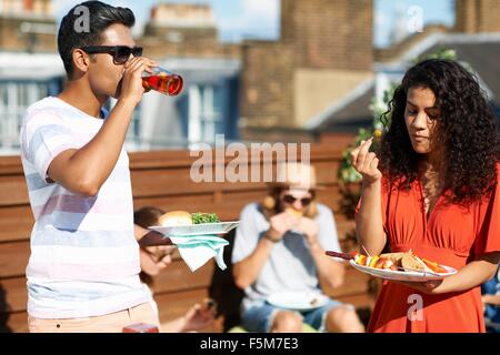 Les amis de manger et boire des aliments partie at rooftop party Banque D'Images