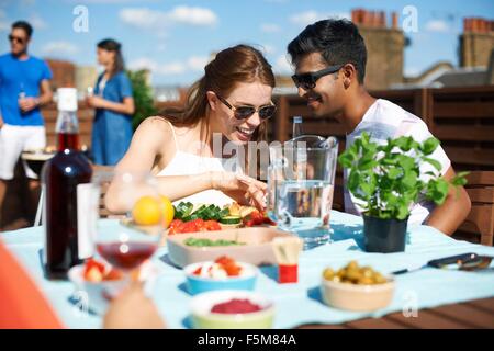 Couple chatting et flirting at rooftop party Banque D'Images