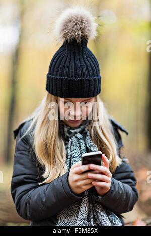 Girl using smartphone en forêt d'automne Banque D'Images