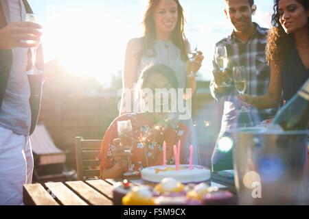 Friends at outdoor party blowing out candles on cake Banque D'Images