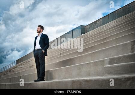 Low angle view of mid adult man sur les mesures portant costume, les mains dans les poches à la voiture Banque D'Images