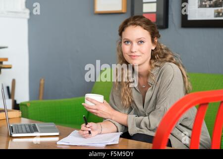 Portrait of young female designer sur canapé bureau Banque D'Images