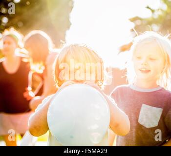 Young boy Blowing up balloon in garden Banque D'Images