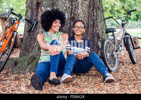 Portrait de femme mature et son fils assis contre l'arbre du parc Banque D'Images