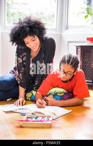Femme mature et fils dessin dans sketchbook sur plancher du salon Banque D'Images