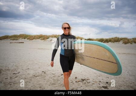 Senior woman walking on beach, surf Transport Banque D'Images