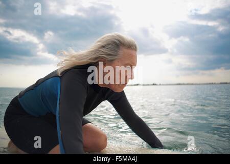 Senior woman on surf en mer, paddleboarding Banque D'Images