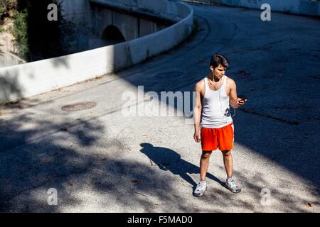 Jogger sélection de musique sur smartphone, Arroyo Seco, Pasadena, Californie, USA Banque D'Images