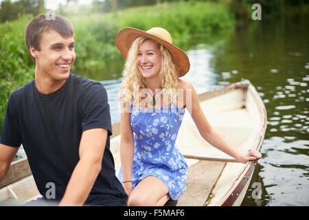Jeune couple en bateau à rames sur la rivière rural Banque D'Images