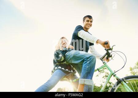 Low angle portrait of young couple on bicycle Banque D'Images