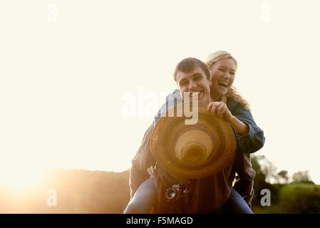 Portrait of young man giving girlfriend a piggyback