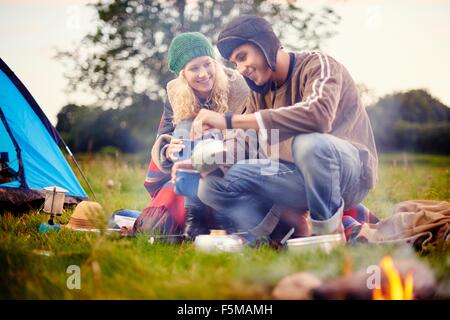 Jeune couple pouring tea camping Banque D'Images