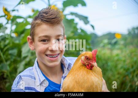 Portrait of boy in field holding hen Banque D'Images