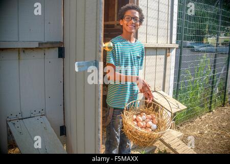 Portrait of boy in poulailler avec panier d'œufs Banque D'Images