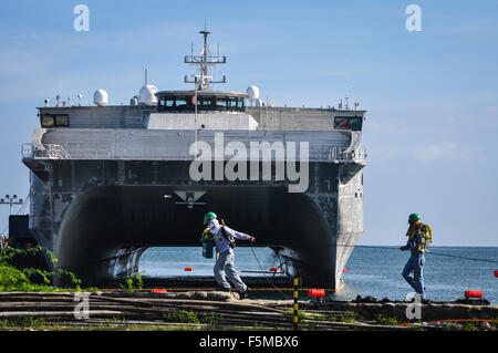 Tirez les travailleurs recevables comme ils passent devant l'USNS Millinocket, un transport maritime militaire conjointe commande navire grande vitesse, amarré au th Banque D'Images