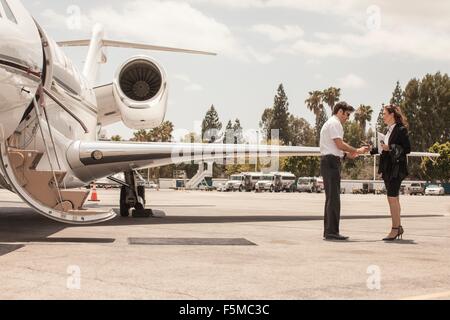 Female businesswoman shaking hands with private jet pilot à l'aéroport Banque D'Images