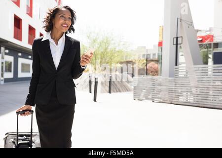 Young businesswoman pulling suitcase, en plein air, Banque D'Images