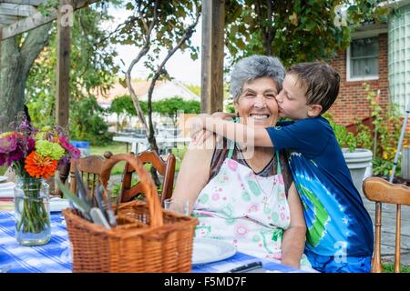 Boy hugging et embrassant la joue de sa grand-mère à manger de tomate festival Banque D'Images