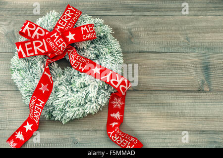 Couronne de Noël avec Red Ribbon bow sur fond de bois. Décoration de fête. Joyeux Noël ! Tons style vintage photo Banque D'Images