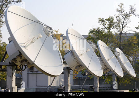 Quatre antennes satellites haute puissance face au ciel. Banque D'Images