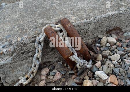 Vieux bateau rouillé point d'ancrage dans le béton avec du métal rouillé et crochets métal chaîne couvertes de petites mouches de glace Banque D'Images