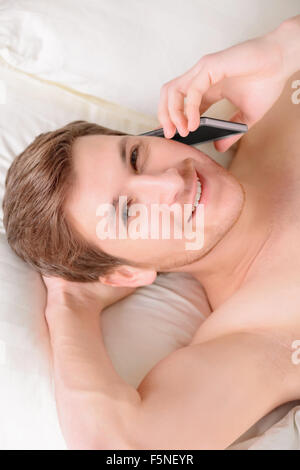 Guy au lit et parlant au téléphone mobile. Banque D'Images